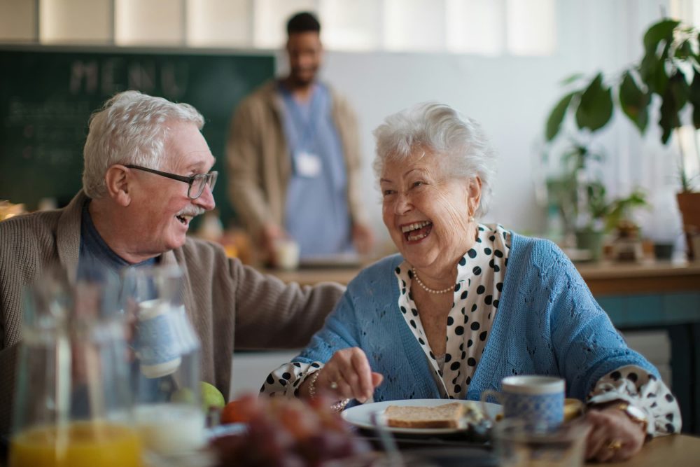 Lachende senioren aan tafel tijdens een gezellige maaltijd